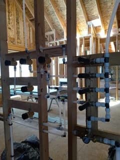 Multiple plumbing distribution manifolds mounted within open wall framing