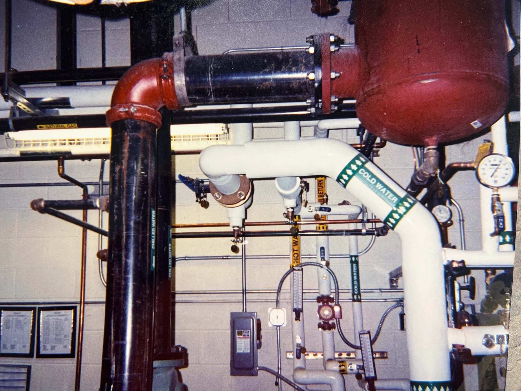 Mechanical-room piping with insulated water lines, copper connections, and pressure gauges